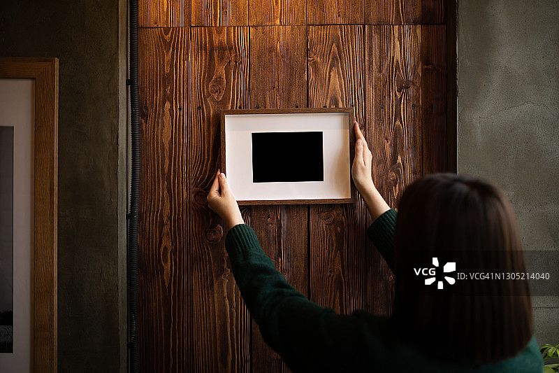 女人扶着墙上的相框图片素材