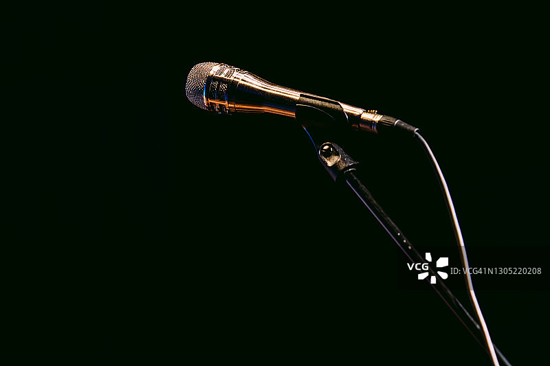 黑色背景上的银色麦克风支架和麦克风图片素材