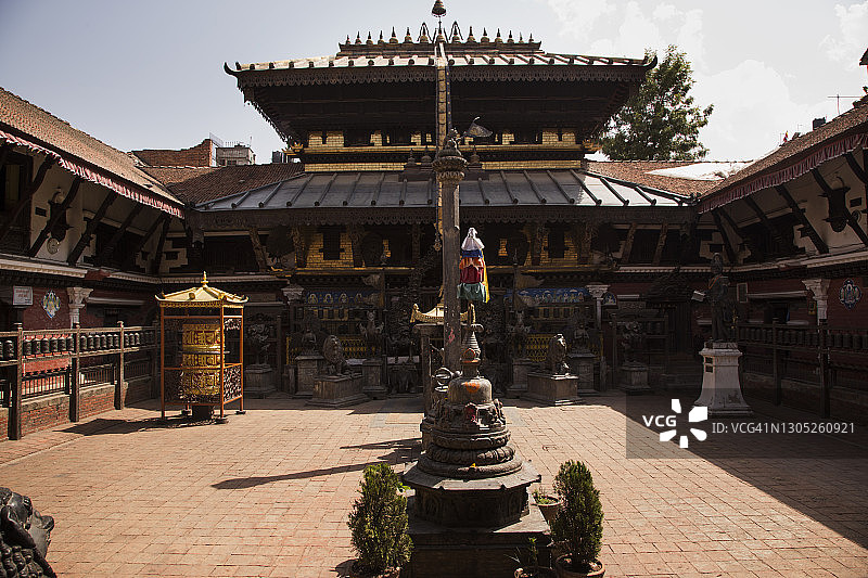 尼泊尔加德满都帕坦拉利特普尔鲁德拉瓦纳·马哈维哈新瓦尔佛寺庭院中，华丽的镀金寺庙建筑，配有大型祈祷轮和小佛塔图片素材