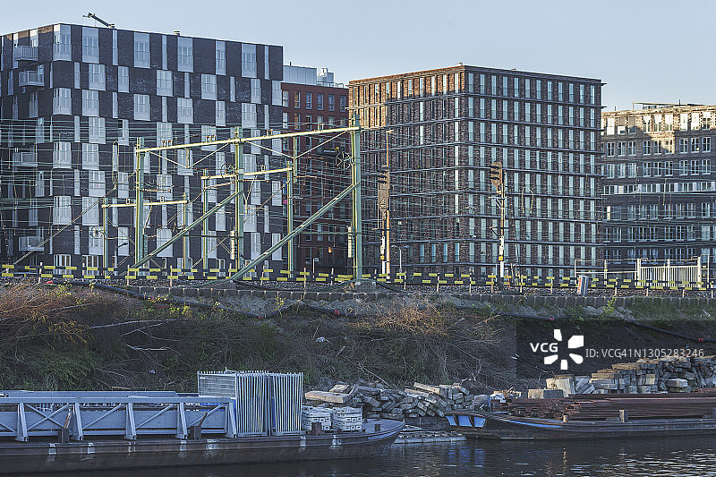 现代主义办公楼、铁路线和带有驳船的工业运河图片素材