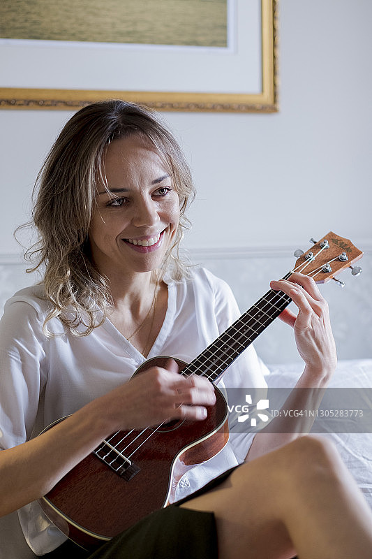 年轻女子在家弹奏尤克里里图片素材
