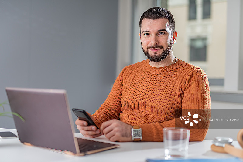 商人手持智能手机看着镜头图片素材