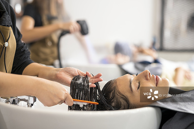 顾客在美容院享受美发师的洗发服务图片素材