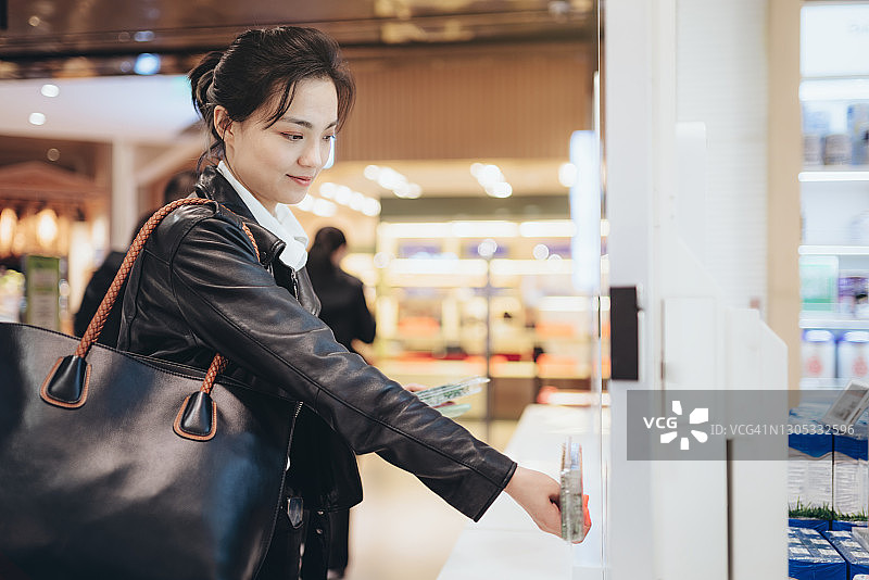 女孩在超市自助结账处扫描葡萄酒图片素材