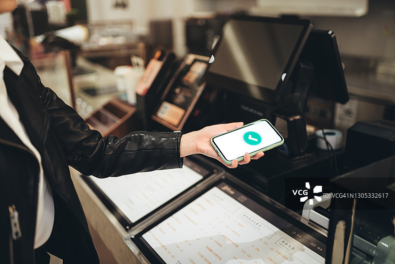 在咖啡馆用手机支付的亚洲年轻女性图片素材