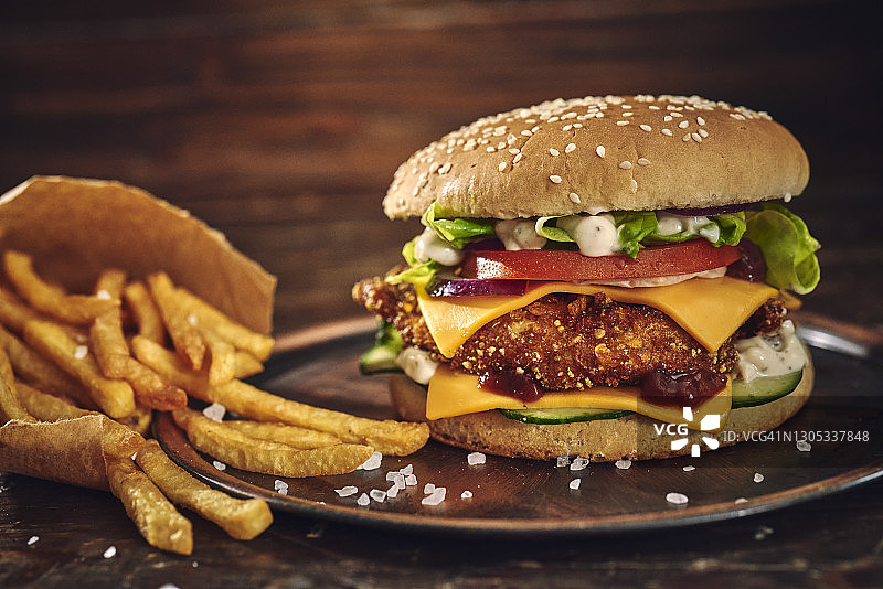 香脆炸鸡汉堡，配奶酪、番茄、洋葱和生菜图片素材