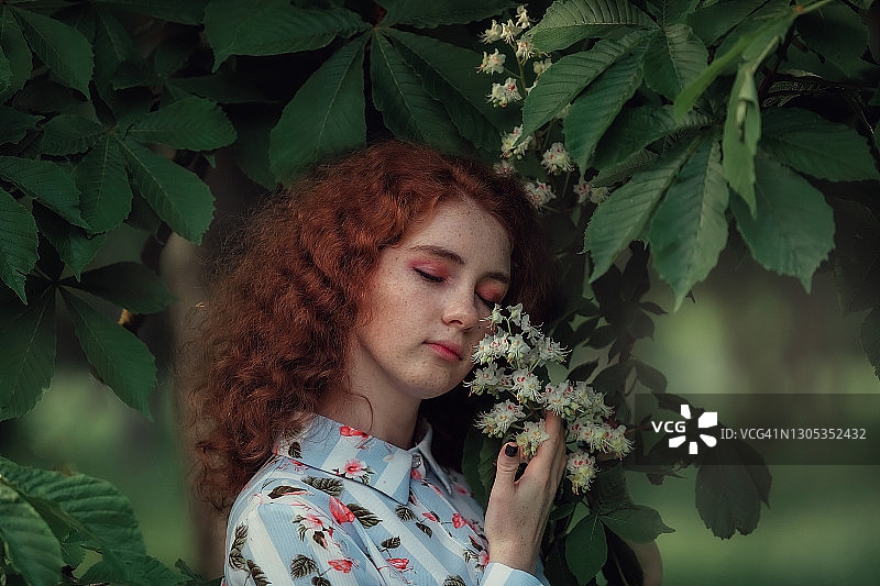 在开花的栗子树旁边的红发女孩肖像图片素材