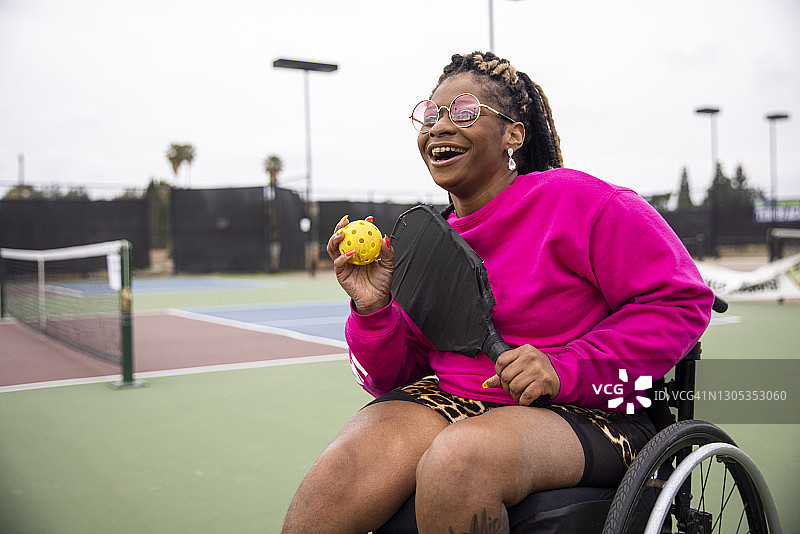 坐在轮椅上的年轻黑人残疾妇女与朋友一起玩匹克球图片素材