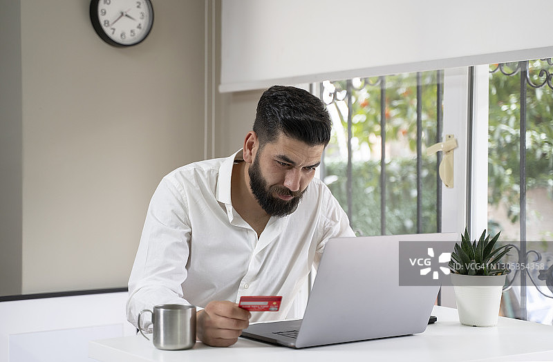 中东男子使用笔记本电脑和信用卡进行网购图片素材