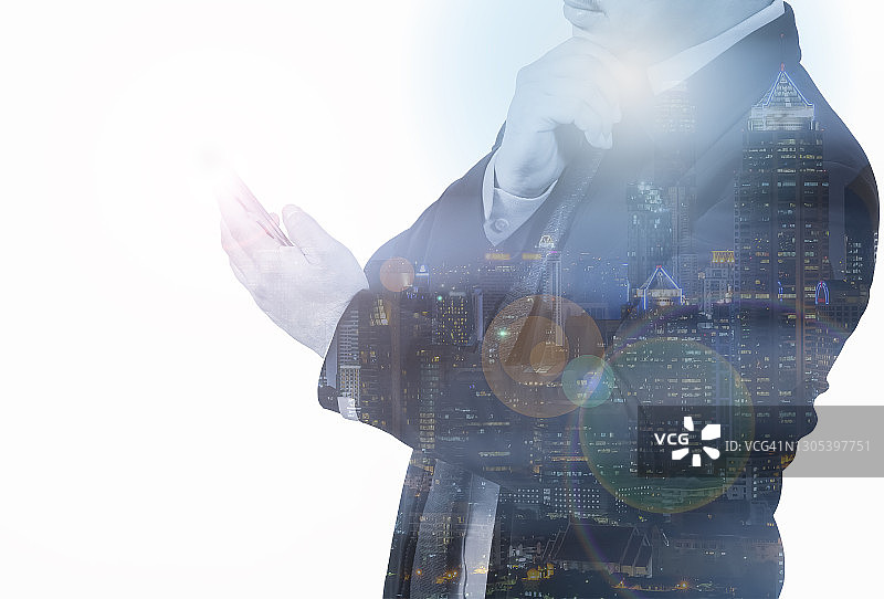 双重曝光：商务人士使用智能手机，城市景观背景。交易和互联网连接概念图片素材