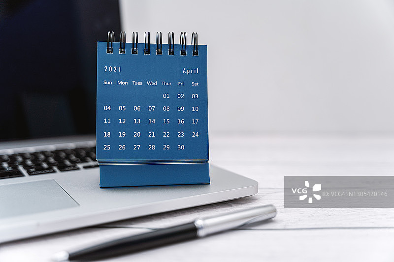 白色木桌笔记本电脑上的2021年4月小日历图片素材