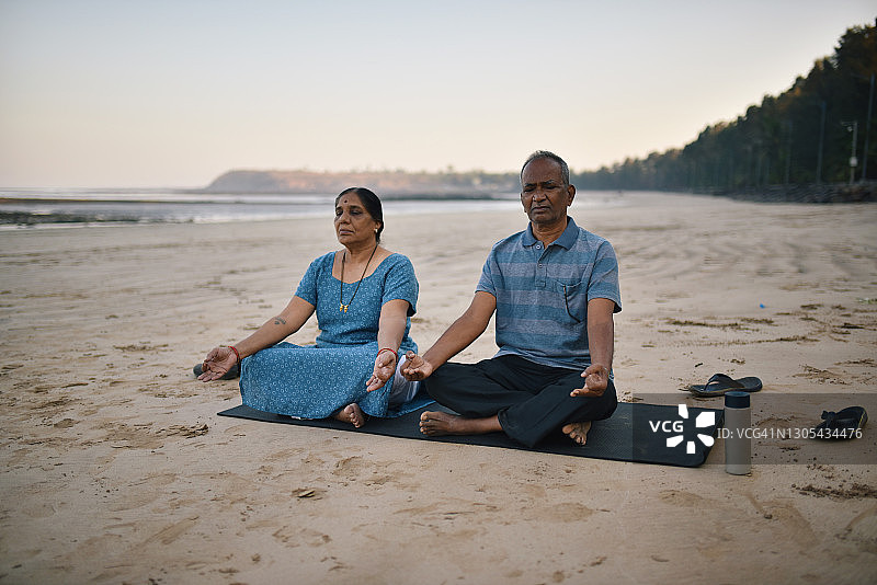 年长夫妇在海滩上冥想图片素材