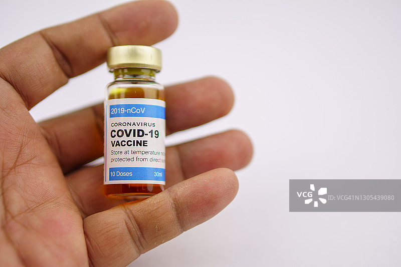 手持新冠疫苗瓶的手部特写图片素材