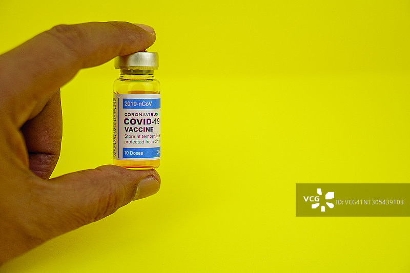 手持新冠疫苗瓶的手部特写图片素材