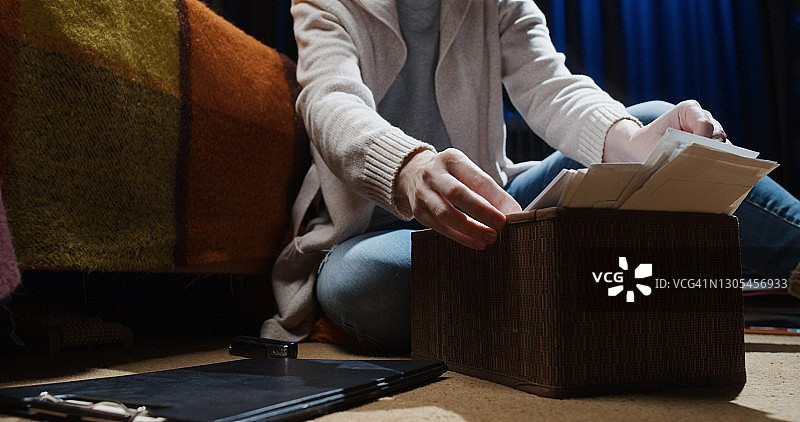 居家办公的女人，她坐在地板上在档案中寻找文件图片素材