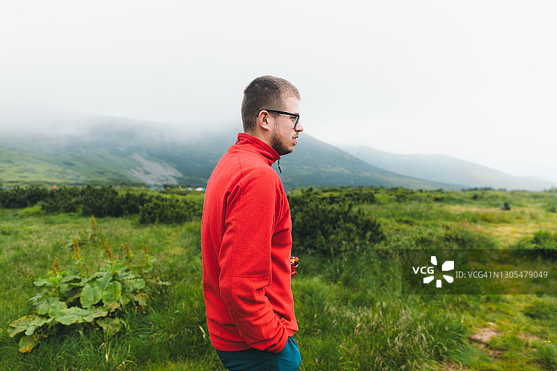 在雾蒙蒙的日出时分，在山中行走的年轻旅行者图片素材