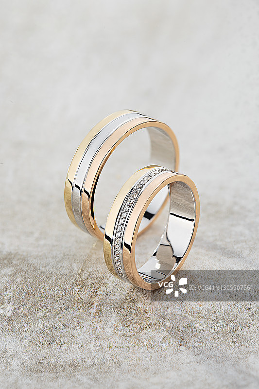三枚金色结婚戒指：镶嵌钻石的银色、玫瑰金和黄金戒指图片素材