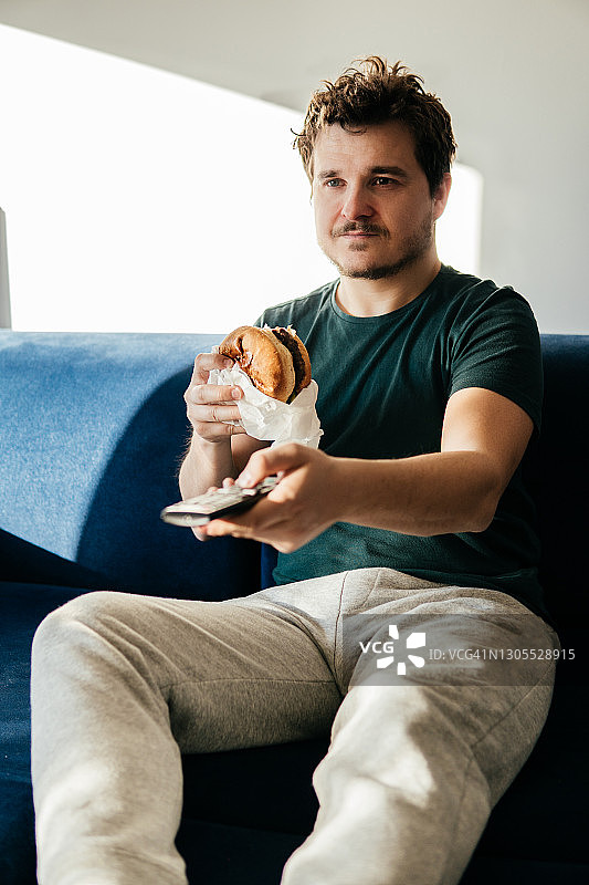 男人在家看电视吃炸薯条图片素材