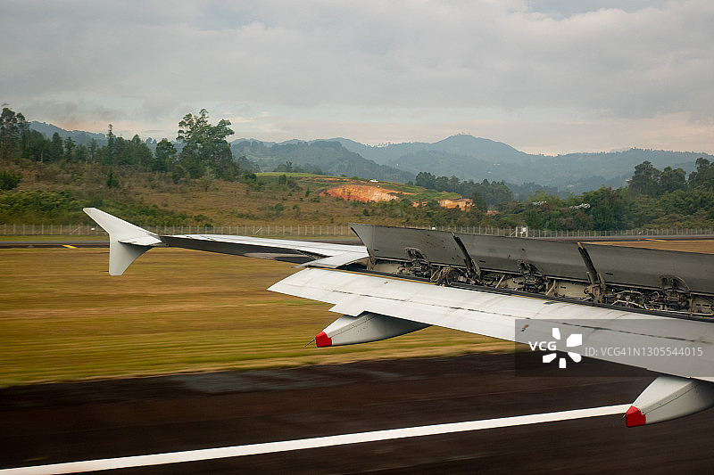 飞机起飞掠过跑道，背景是肥沃的黄色土地和多云的天空图片素材