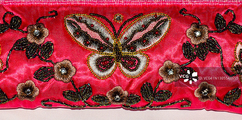 粉色面料上蝴蝶和花朵的彩色珠饰图片素材