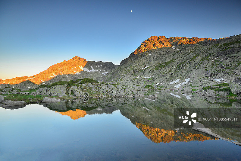 山峰上的霞光倒映在清澈的冰川湖上图片素材