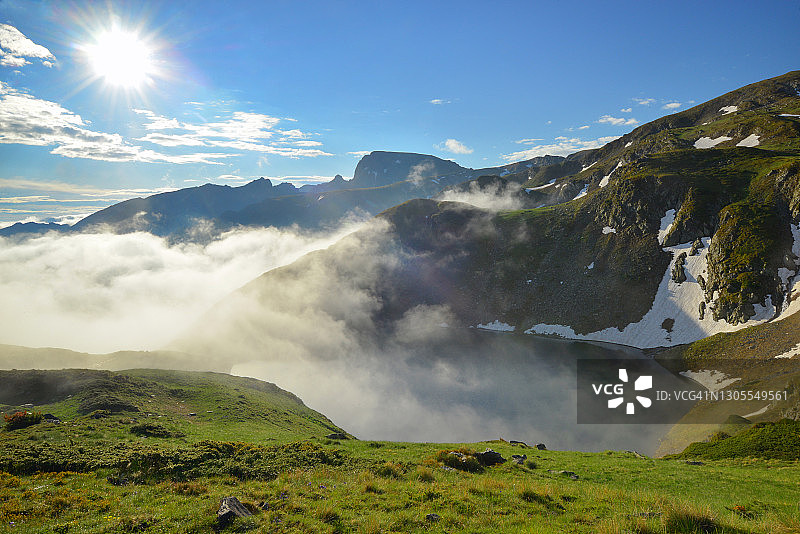 阳光明媚的山中，可欣赏覆盖着雾气的冰川湖美景图片素材
