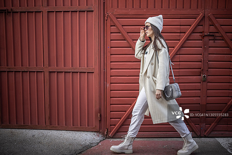 走在红色金属墙前人行道上的女士图片素材