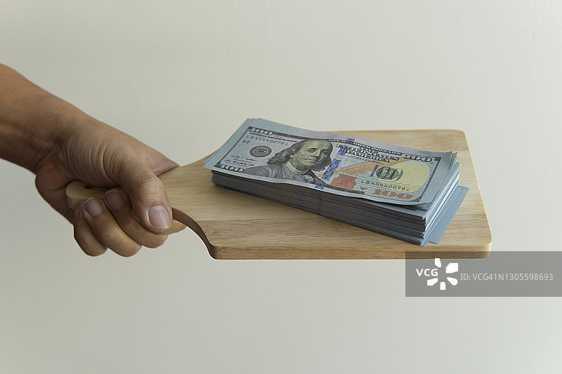 木制餐盘上大量美元纸币图片素材