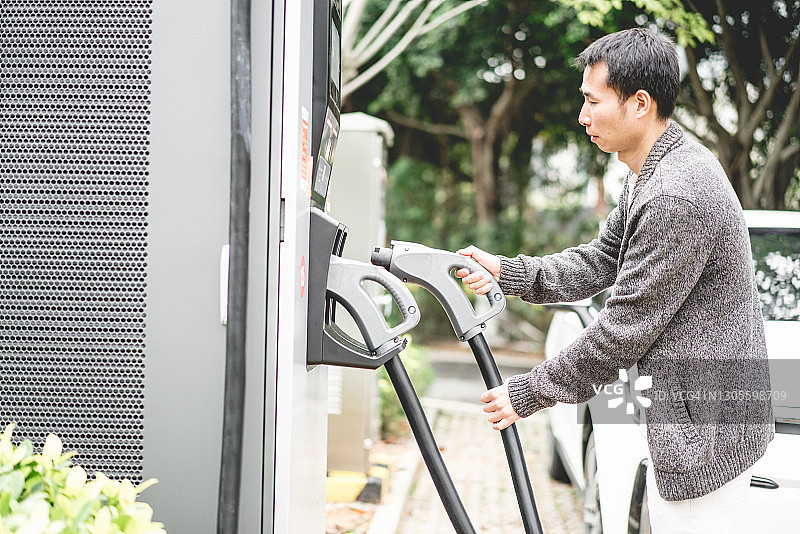 亚洲男人正在给汽车充电图片素材