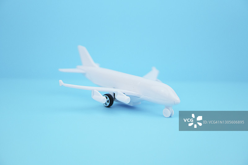 蓝色背景上的白色塑料飞机，商务旅行概念图片素材