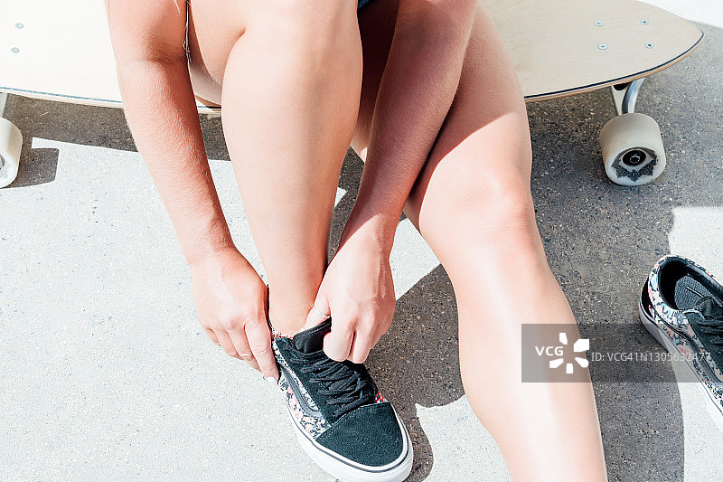 坐在长板滑板上穿鞋的女人图片素材