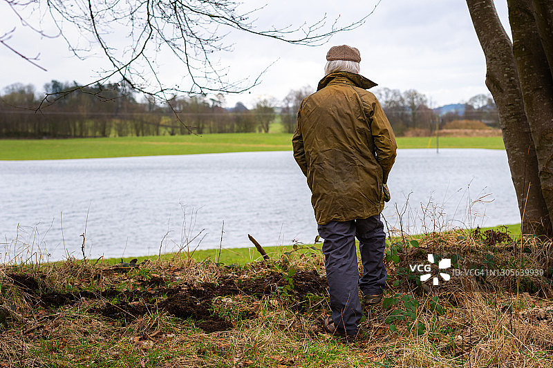 农民看着被洪水淹没的田地的背影图片素材