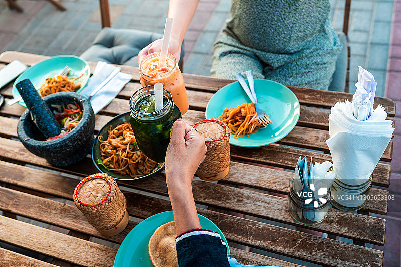 女士享用泰国美食，举杯泰国奶茶图片素材