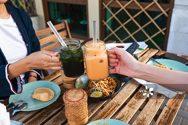 女士享用泰国美食，举杯泰国奶茶图片素材