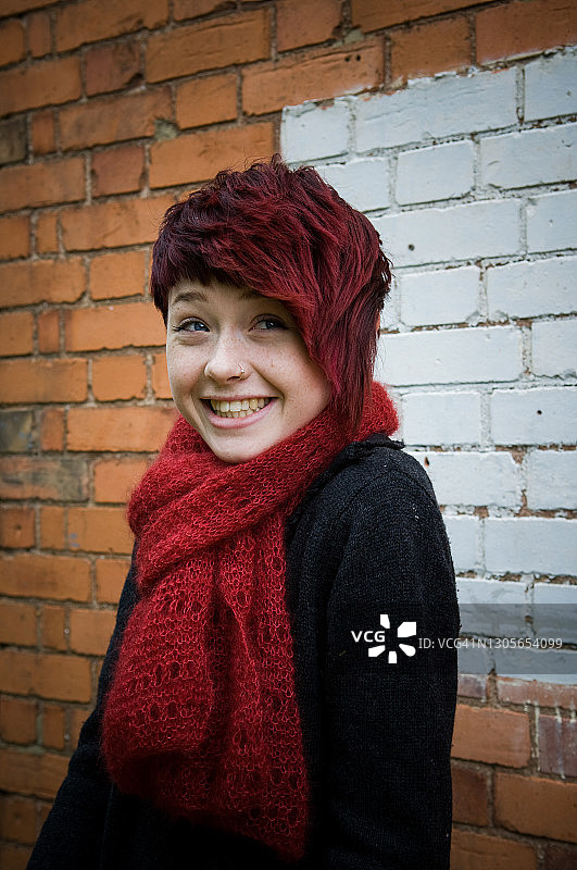 在砖墙前微笑的少女图片素材