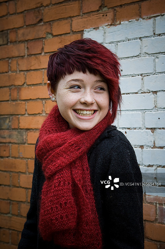 在砖墙前微笑的少女图片素材