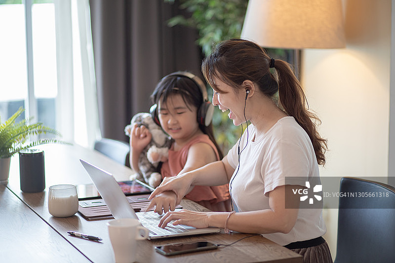 在餐厅工作的中国女商人，女儿在她旁边玩耍图片素材