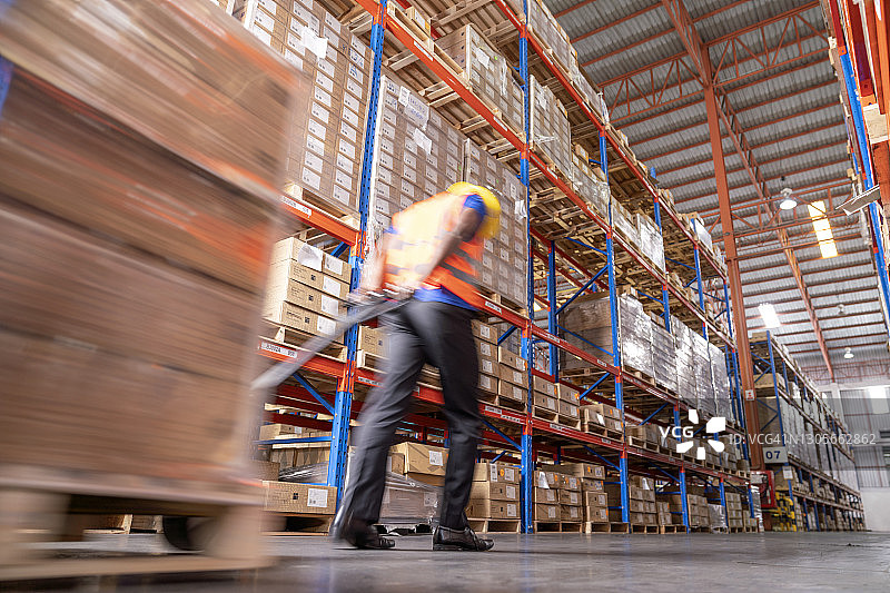 仓库工人移动托盘上箱子的动态模糊照片图片素材