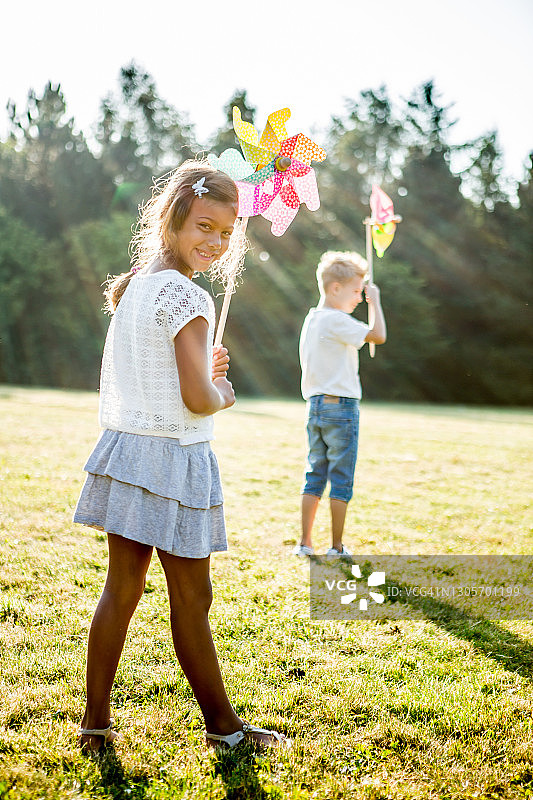儿童在草地上玩风车图片素材