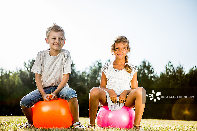 孩子们在草地上用充气跳跃器跳跃图片素材
