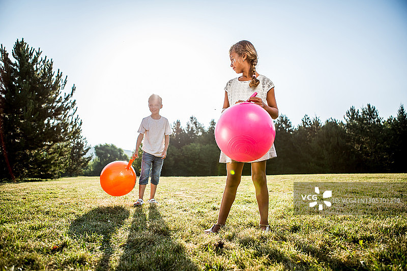 孩子们在草地上用充气跳跃器跳跃图片素材