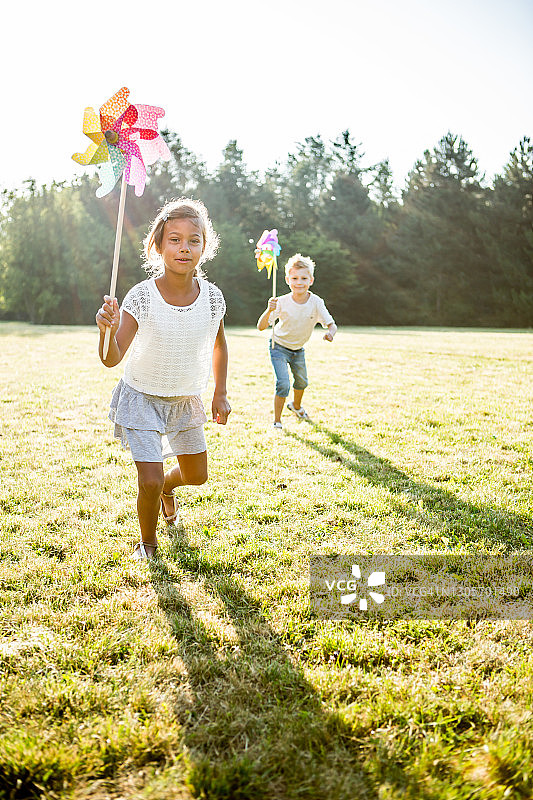 儿童在草地上玩风车图片素材