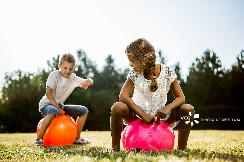 孩子们在草地上用充气跳跃器跳跃图片素材