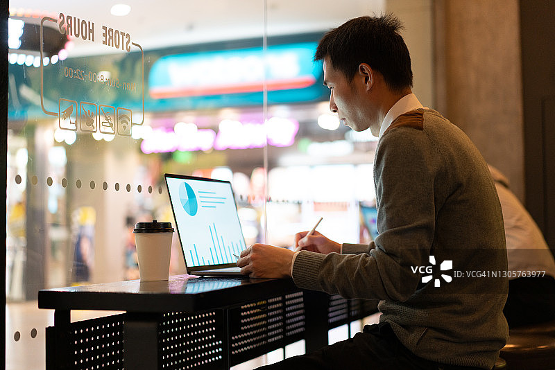 在商店里使用笔记本电脑的亚洲男人图片素材