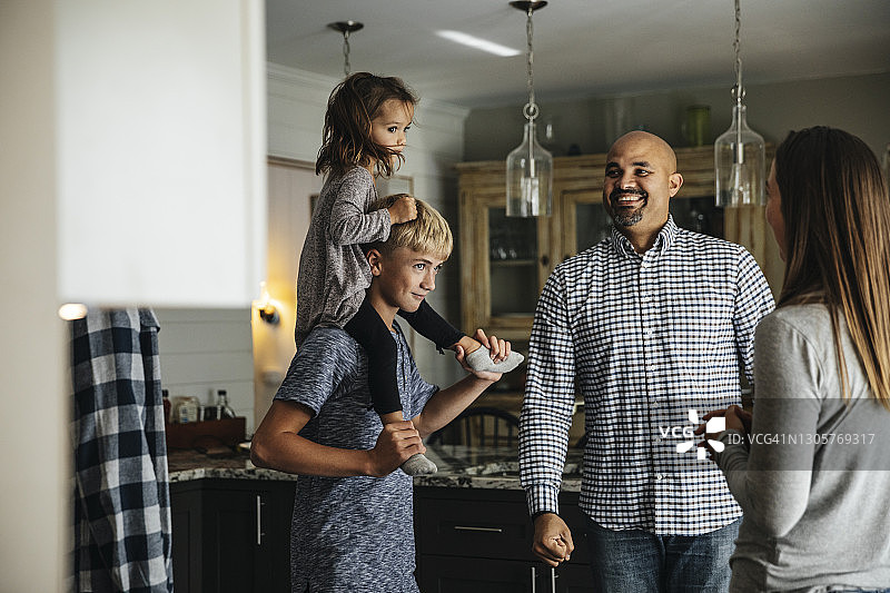 幸福的父母看着扛着女孩的男孩图片素材
