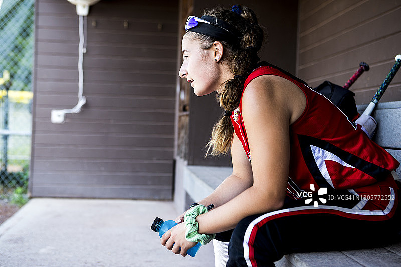 坐在休息区里的青少年垒球运动员肖像图片素材