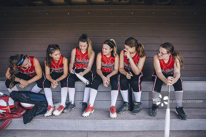 坐在休息区长凳上的少女垒球队图片素材