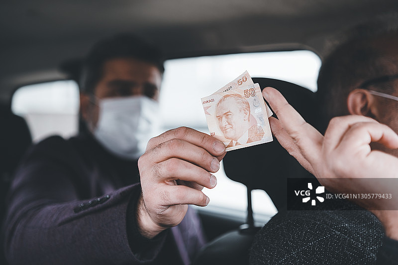 戴着防护口罩乘坐出租车，用土耳其里拉支付车费的成熟商人图片素材