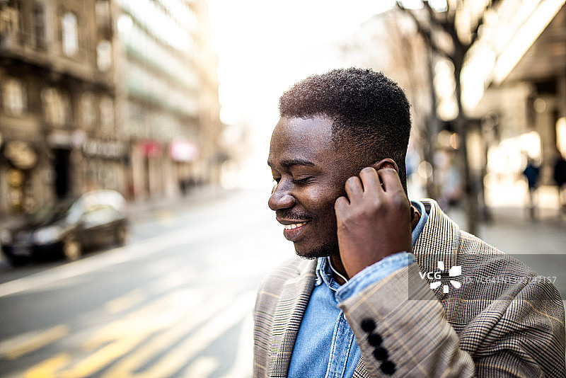 快乐的年轻商人在等公共汽车时听音乐图片素材