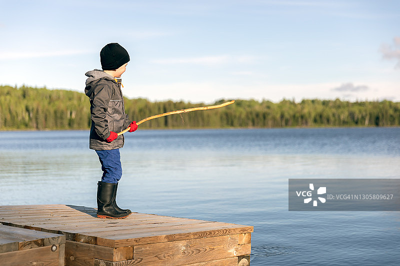 在魁北克鲁安-诺兰达马蒂萨德湖边，拿着木棍眺望的小男孩图片素材